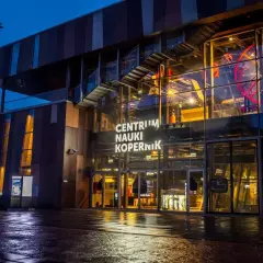 Centrum Nauki Kopernik nocą, z widocznym wejściem i fragmentem ekspozycji.