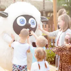 Dzieci bawią się z pluszową owcą. Idealne miejsce, gdzie jechać w niedzielę z rodziną.