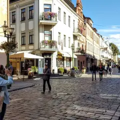 Spacer po urokliwej uliczce w Kownie, gdzie leży to piękne miasto. Kobieta robi zdjęcie zabytkowej kamienicy.