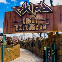 Wejście do ekipy rollercoaster "Light Explorers" w Energylandii. Drewniany szyld z napisem i widokiem na tor kolejki górskiej.