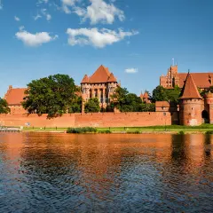 Potężny zamek w Malborku odbija się w wodzie. Zastanawiasz się, ile trwa zwiedzanie zamku w Malborku?
