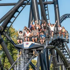 Ludzie na kolejce górskiej w Energylandii, z wodą tryskającą z przodu wagonika. Taka przejażdżka to świetny pomysł na wykorzystanie biletu rocznego Energylandia!