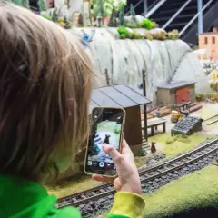 Dziecko fotografuje telefonem miniaturową wioskę w parku miniatur Wrocław.