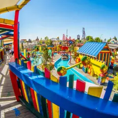 Kolorowy park rozrywki Energylandia, pełen atrakcji i bajkowych miejsc w Polsce. Dzieci pływają łódkami po wodnej trasie wśród kolorowych domków i zjeżdżalni.