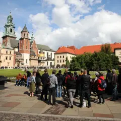 Grupa turystów zwiedza Wawel. Sprawdzają wawel bilety cennik przed wejściem.