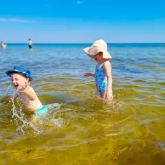 Dzieci bawią się w wodzie na plaży, jednej z urokliwych miejscowości blisko Gdańska.