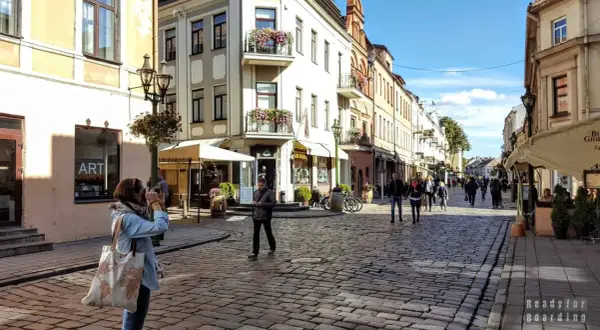 Spacer po urokliwej uliczce w Kownie, gdzie leży to piękne miasto. Kobieta robi zdjęcie zabytkowej kamienicy.