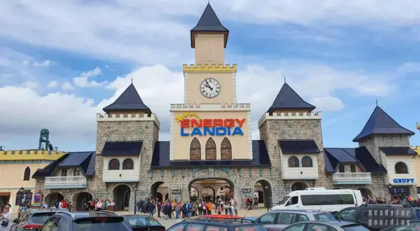 Wrocław Energylandia wita gości zamkową architekturą i kolorowym logo. Tłumy ludzi i zaparkowane samochody sugerują początek ekscytującego dnia.
