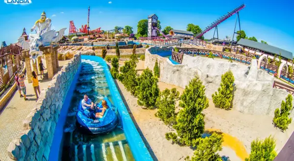 Energylandia: wodna przejażdżka dla całej rodziny, idealna dla dzieci do 140 cm. W tle widać rollercoastery i wieżę widokową.