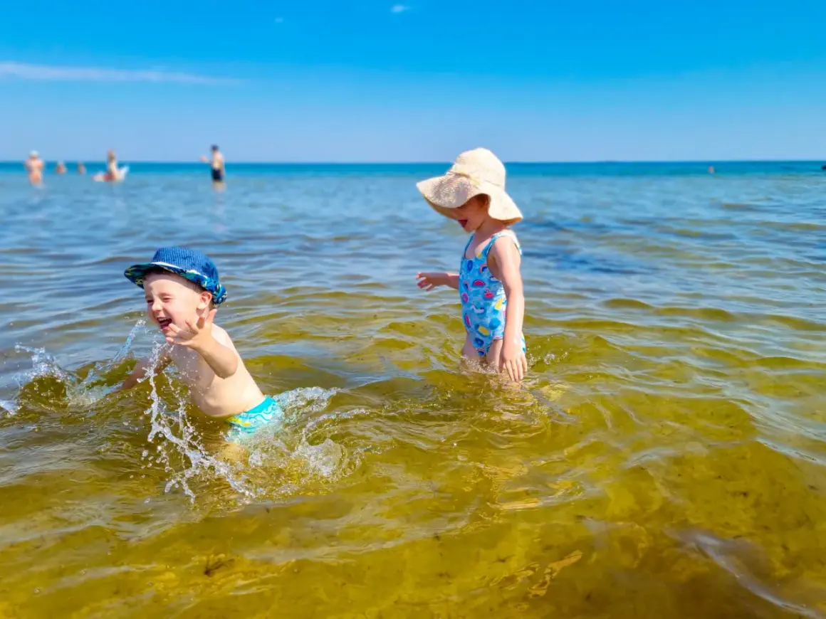 Dzieci bawią się w wodzie na plaży, jednej z urokliwych miejscowości blisko Gdańska.