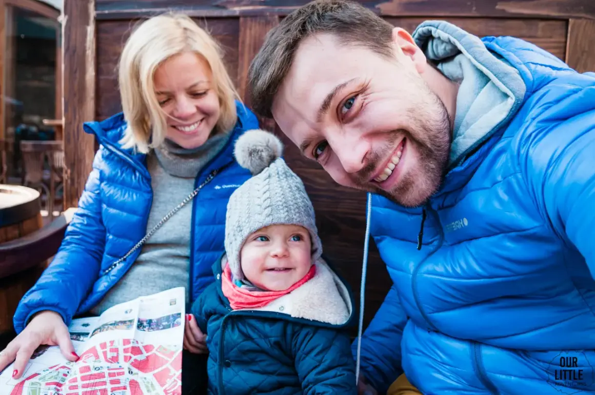Rodzina zwiedza Lwów na Ukrainie. Uśmiechnięci rodzice i dziecko z mapą.