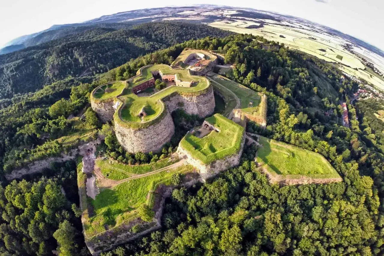 Forteca na wzgórzu, jeden z najpiękniejszych zamków na Dolnym Śląsku, otoczona lasem, z widokiem na pola i góry.