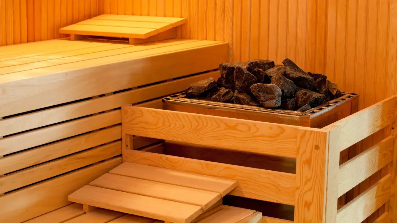 Drewniana sauna z kamieniami do podgrzewania. Idealne miejsce na relaks, choć niektórzy wolą połączyć saunę z alkoholem.