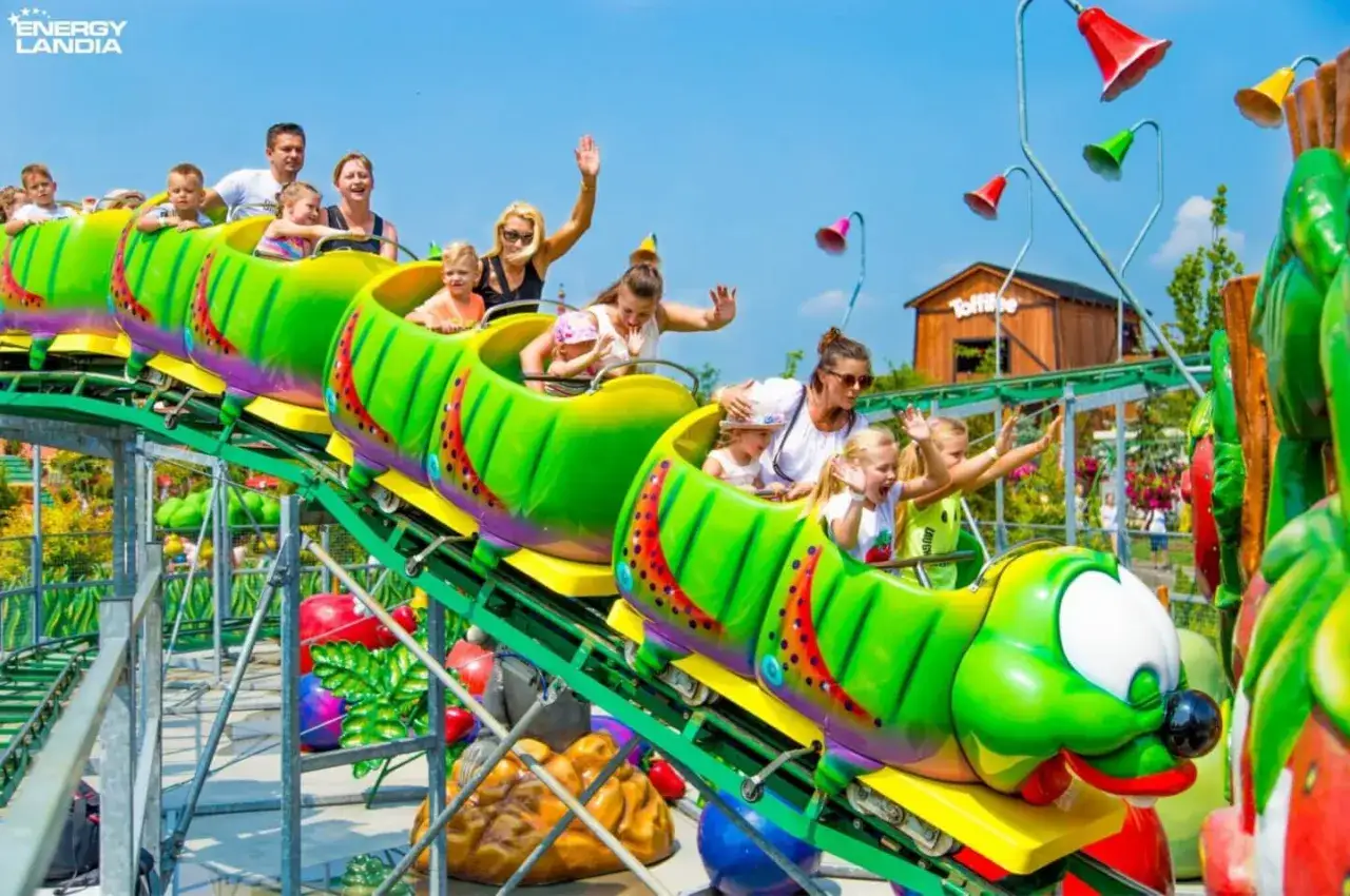 Rodzina na zielonym wagoniku w kształcie gąsienicy w Energylandii. Szukaj energylandia kod rabatowy na kolejną wizytę!