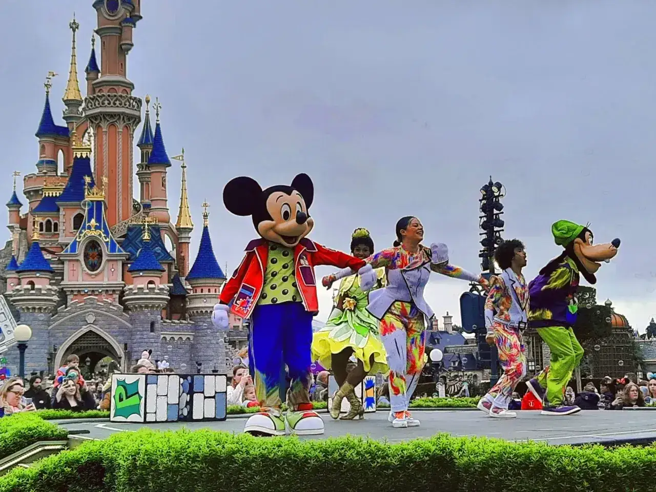 Myszka Miki i przyjaciele tańczą na scenie przed zamkiem w Disneylandzie. Wspaniała przygoda czeka na posiadaczy biletów do Disneylandu!
