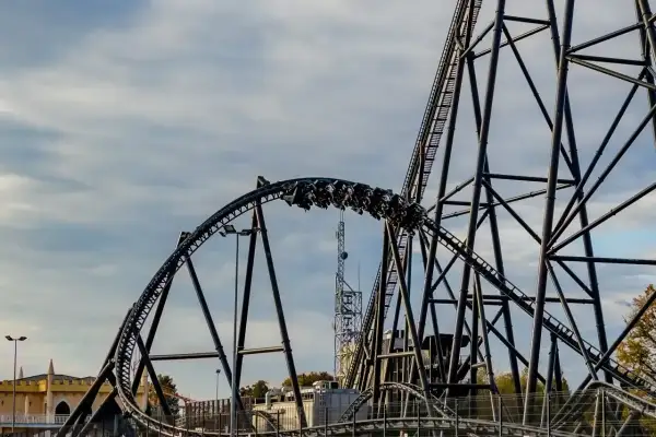 Pasażerowie Hyperion roller coaster pędzą po stalowej konstrukcji, chmury na niebie dodają dramatyzmu.